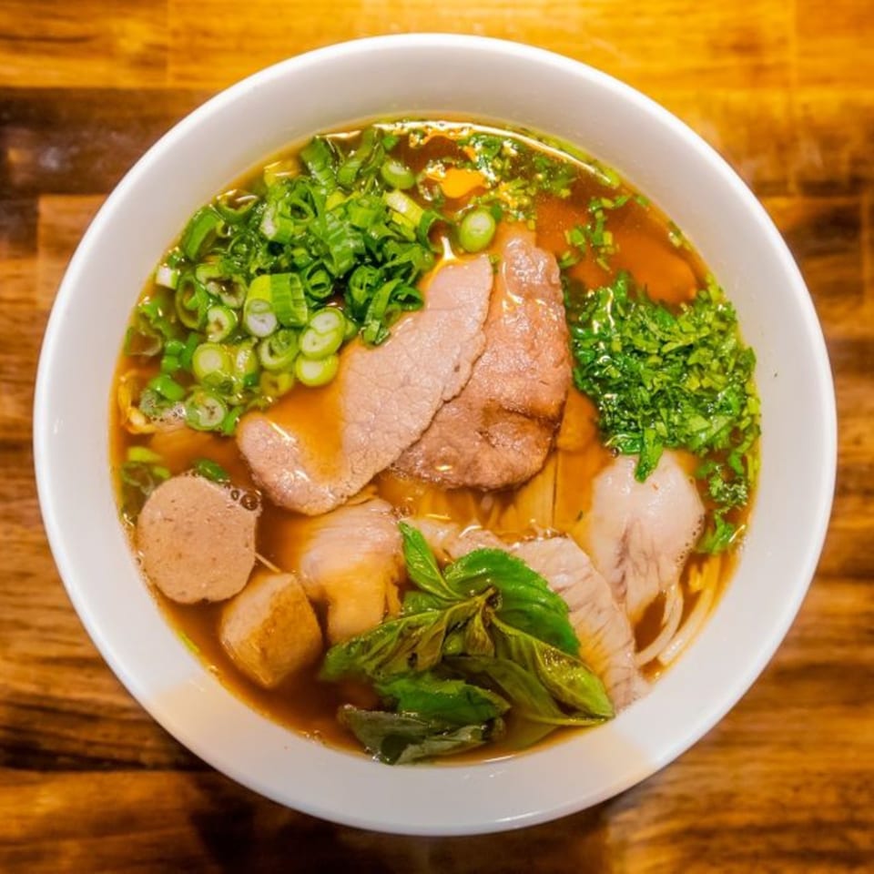 A bowl of Miso's Japanese ramen with sliced meat, meatballs, tofu, and fresh herbs.