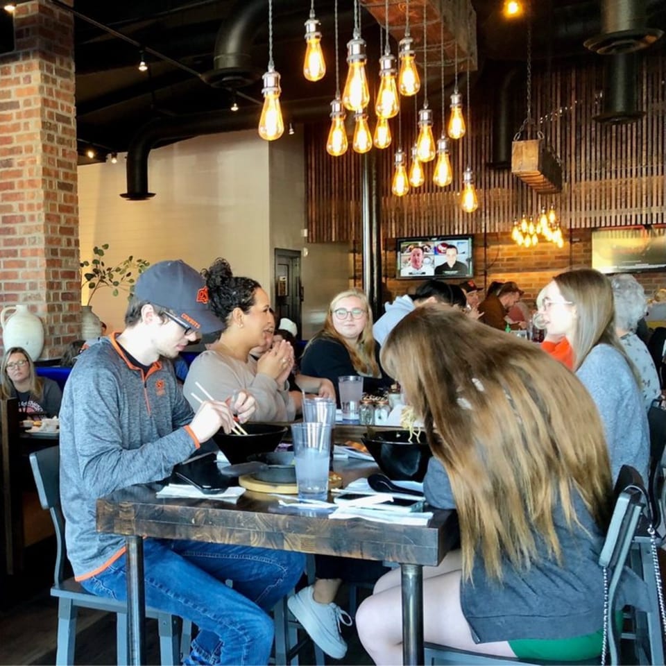 Diners enjoying Japanese cuisine at Miso, with warm lighting and brick accents.